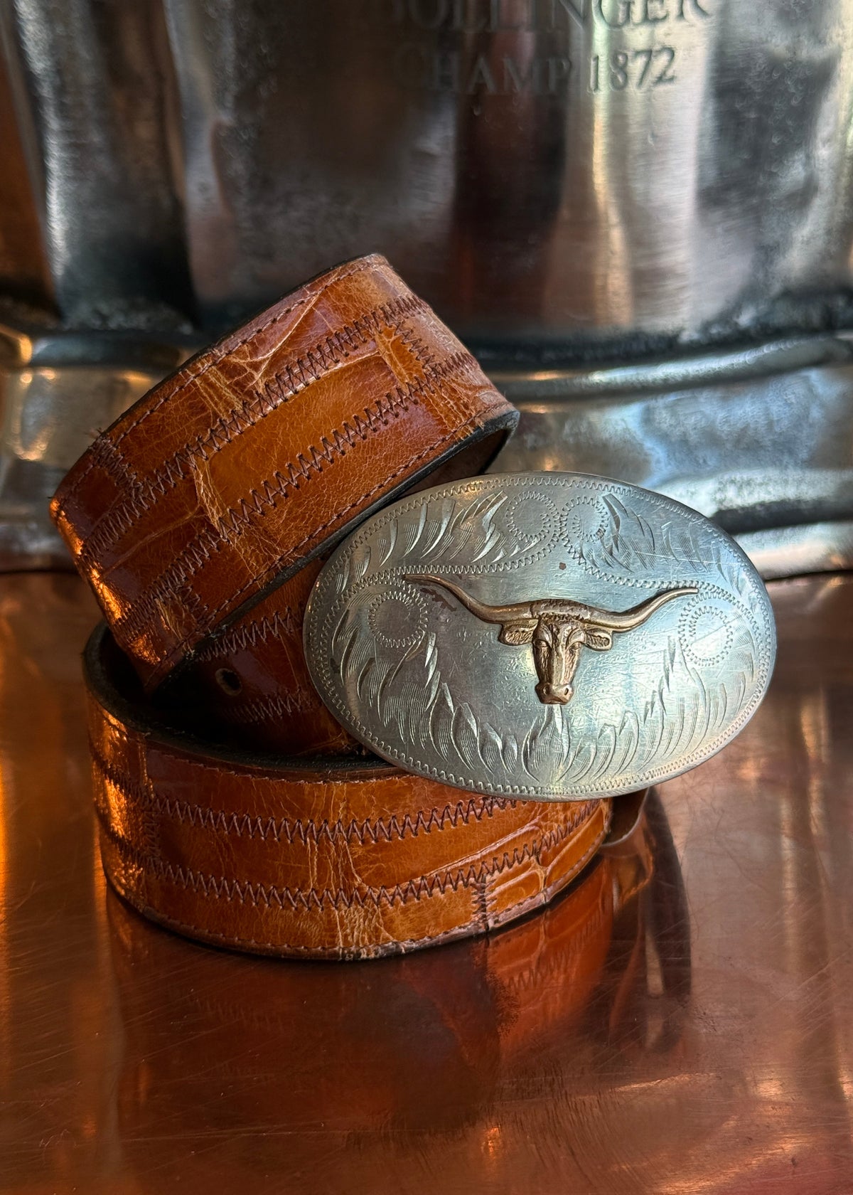 Longhorn belt buckle on a orange belt strap.