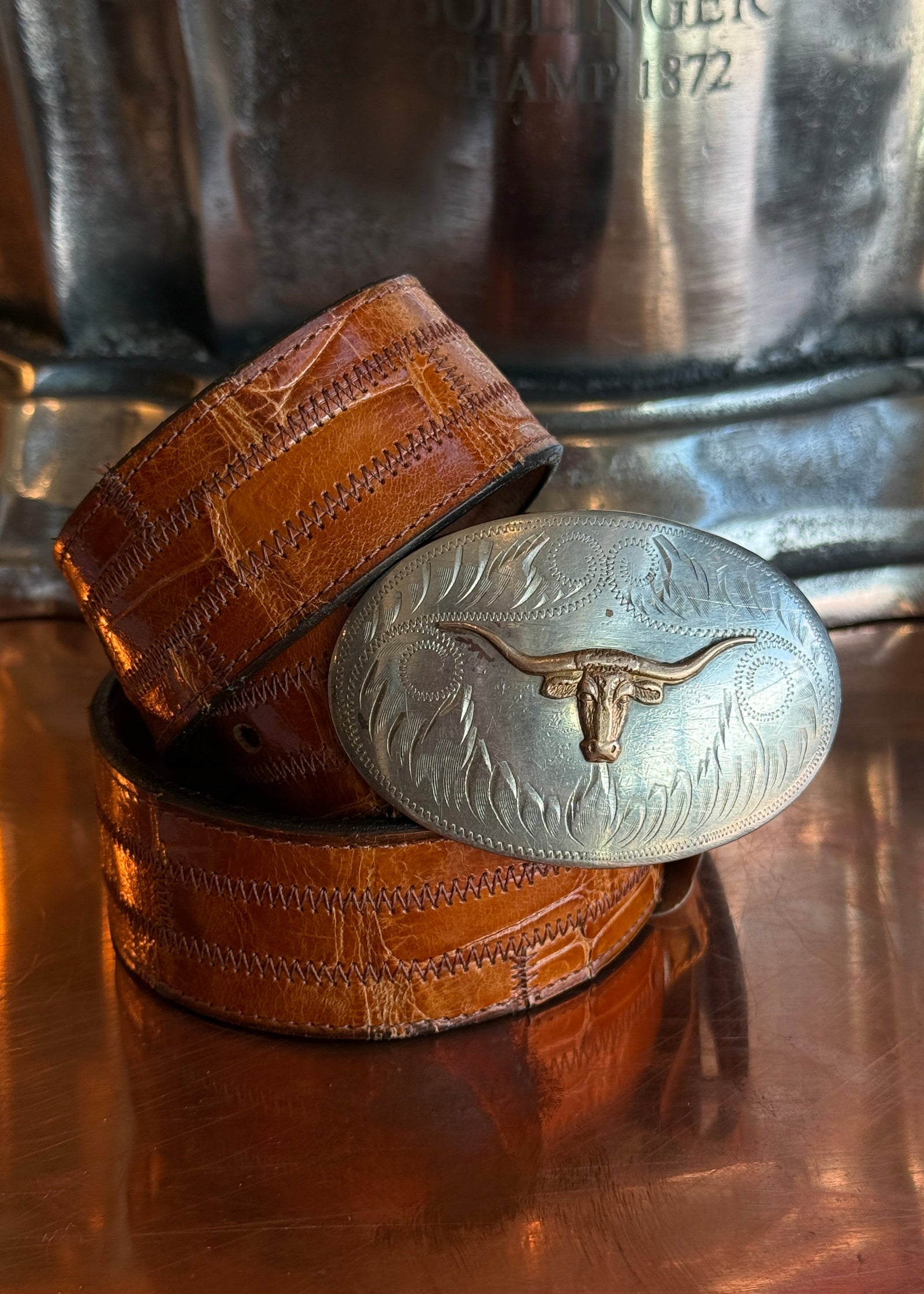 Longhorn belt buckle on a orange belt strap.